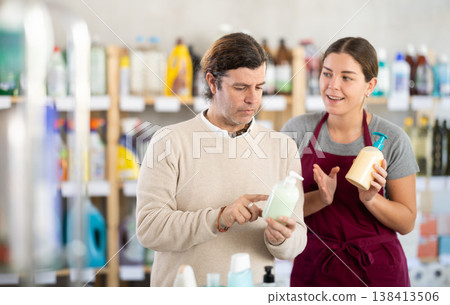 Young female sales assistant offering liquid soap to male customer Young female sales assistant offering liquid soap to male customer 138413506