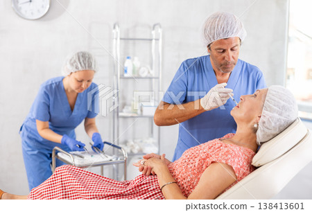 Woman applying rejuvenating treatments by male doctor. 138413601