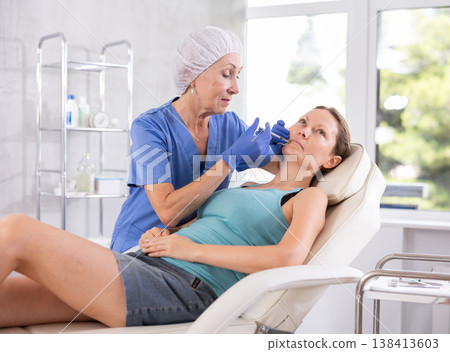 Woman getting procedure of injection contouring and for facial correction in clinic Woman getting procedure of injection contouring and for facial correction in clinic 138413603