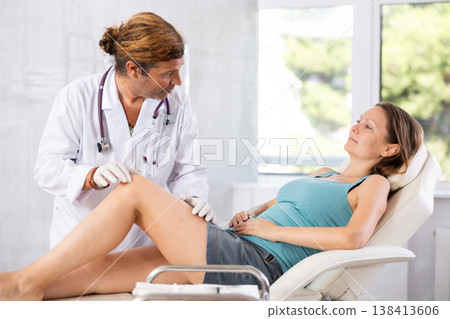 Doctor in medical gloves exam woman's legs. Doctor in medical gloves exam woman's legs. 138413606