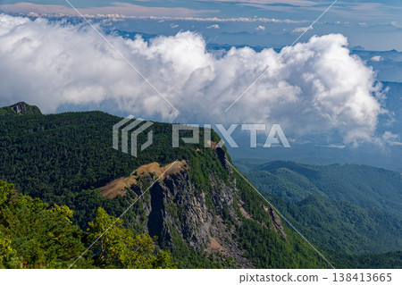 The rocky cliffs of Inago-dake and the cloud-filled mountain range as seen from Tengu-dake in the Yatsugatake mountain range. The rocky cliffs of Inago-dake and the cloud-filled mountain range as seen from Tengu-dake in the Yatsugatake mountain range. 138413665