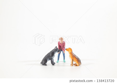 Miniature figure interacting with two seated dogs Miniature figure interacting with two seated dogs 138413720