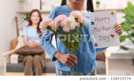Daughter presenting flowers and card for Mother's Day Daughter presenting flowers and card for Mother's Day 138414574