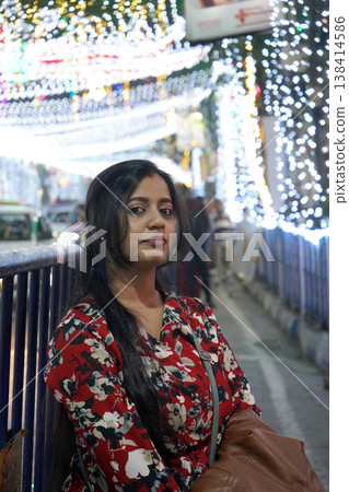 Beautiful Indian woman in floral dress posing against festive city night lights in Kolkata Beautiful Indian woman in floral dress posing against festive city night lights in Kolkata 138414586