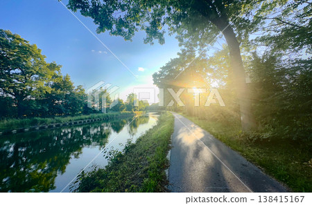 Rijkevorsel, Antwerpse Kempen, Belgium, Warm glow bathes lush bank and reflective water surface 138415167