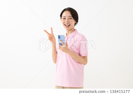 A woman making a peace sign while holding her smartphone. A woman making a peace sign while holding her smartphone. 138415277