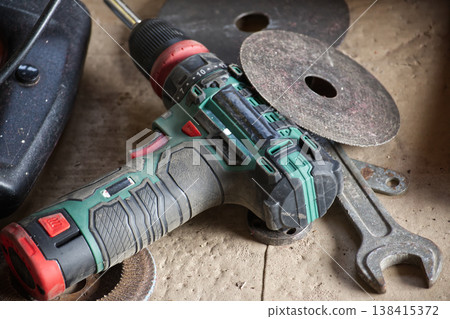 Cordless drill and cutting discs on a dusty workbench, ready for DIY projects Cordless drill and cutting discs on a dusty workbench, ready for DIY projects 138415372