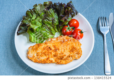 A plate of miso-marinated pork steak, lettuce, and cherry tomatoes; a home-style dish served on a white plate. A plate of miso-marinated pork steak, lettuce, and cherry tomatoes; a home-style dish served on a white plate. 138415524