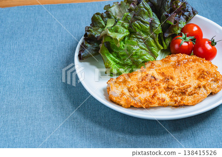 A plate of miso-marinated pork steak, lettuce, and cherry tomatoes; a home-style dish served on a white plate. A plate of miso-marinated pork steak, lettuce, and cherry tomatoes; a home-style dish served on a white plate. 138415526