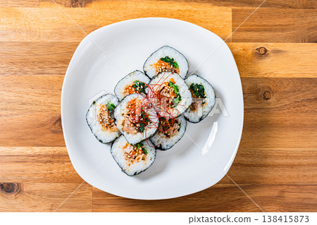 Korean-style seaweed rolls (kimbap) are served on a white plate with plenty of fillings. 138415873