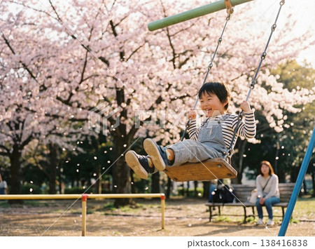 一個男孩在櫻花盛開的公園裡盪鞦韆，臉上露出笑容。 138416838