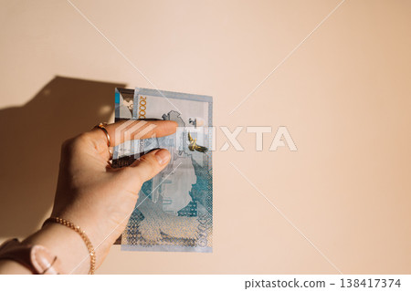 Hand holding Kazakhstani tenge banknotes fanned out on beige background, payment and finance concept Hand holding Kazakhstani tenge banknotes fanned out on beige background, payment and finance concept 138417374