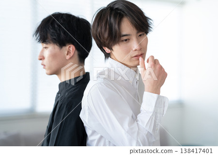 一位年輕男子和朋友在客廳放鬆休息。 138417401