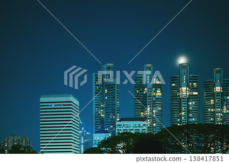 Bangkok skyline with illuminated residential towers and moon at night, Modern cityscape with highrise buildings and glowing windows under night sky Bangkok skyline with illuminated residential towers and moon at night, Modern cityscape with highrise buildings and glowing windows under night sky 138417851