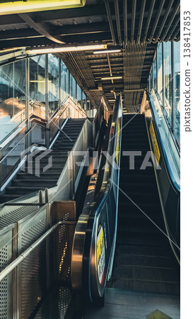 Escalator and stairs in modern metro station interior with industrial design, Urban transport corridor with moving escalator and geometric architecture in city Escalator and stairs in modern metro station interior with industrial design, Urban transport corridor with moving escalator and geometric architecture in city 138417853