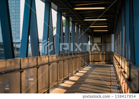 perspective lines of empty pedestrian walkway with industrial structure, urban bridge corridor with metal railings symmetry and sunlight shadows perspective lines of empty pedestrian walkway with industrial structure, urban bridge corridor with metal railings symmetry and sunlight shadows 138417854