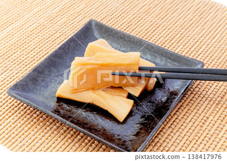 Thick, seasoned bamboo shoots served on a plate, image of being lifted with chopsticks. Thick, seasoned bamboo shoots served on a plate, image of being lifted with chopsticks. 138417976