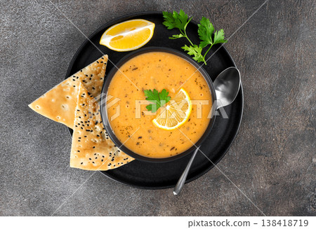 Ezogelin soup with lemon, dried mint, and pide flatbreads on a gray background. Lentil soup. Turkish cuisine. Ezogelin soup with lemon, dried mint, and pide flatbreads on a gray background. Lentil soup. Turkish cuisine. 138418719