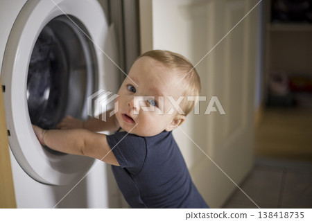 Inquisitive Baby Watching. Little Baby Dressed In Navy Observes Scene Attentively. Infant In Navy Jumpsuit Examines Environment With Curiosity And Playful Spirit Inquisitive Baby Watching. Little Baby Dressed In Navy Observes Scene Attentively. Infant In Navy Jumpsuit Examines Environment With Curiosity And Playful Spirit 138418735