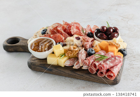 Close-up of charcuterie board with salami, cheeses, olives, jam, nuts and blueberries on rustic wooden board. Close-up of charcuterie board with salami, cheeses, olives, jam, nuts and blueberries on rustic wooden board. 138418741