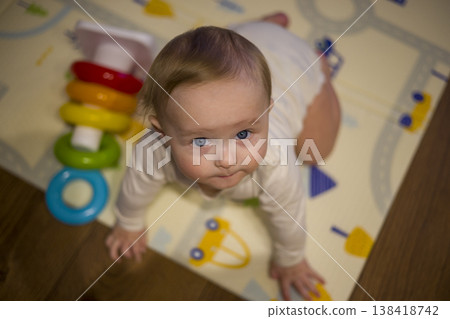 Infant On Vibrant Mat Stretching For Stacking Rings Indoors. Caucasian Infant Maneuvering On Colorful Surface Attempting To Grab Stacking Toy Rings Gracefully Infant On Vibrant Mat Stretching For Stacking Rings Indoors. Caucasian Infant Maneuvering On Colorful Surface Attempting To Grab Stacking Toy Rings Gracefully 138418742