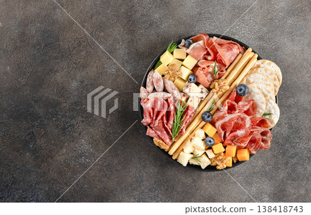 Charcuterie board with assorted cheeses, cured meats, crackers, nuts, berries on dark background. Top view. Copy space. 138418743
