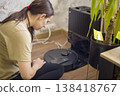 She Vacuums Daily. She Initiates Her Regular Cleaning Process With Vacuum Cleaner. Woman Powers Up Her Vacuum To Commence Her Typical Daily Cleaning Activities 138418767