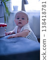 Caucasian Baby Reaching For Colorful Toy On Sofa Edge, Supportive Arm Nearby, Inquisitive Look, Bright Window Light, Indoor Exploration And Hand Eye Coordination Focus verical 138418781