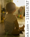 Child Enjoys Gentle Sunlight. Infant Bathed In Warm Glow. Serene Infant Resting Quietly Amid Gentle Illuminated Surroundings And Blurred Family Background verical 138418787