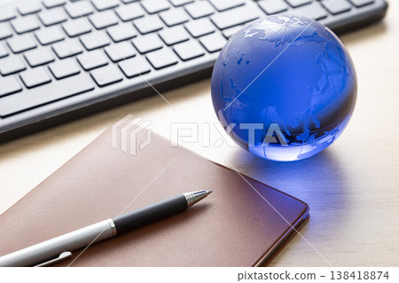 A computer, a notebook, and a glass globe 138418874