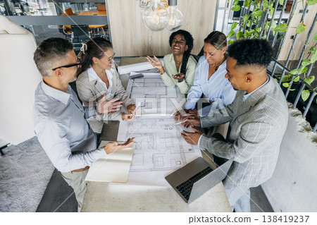Startup founders celebrating milestone over project plan, diverse team Startup founders celebrating milestone over project plan, diverse team 138419237