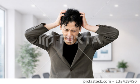 A worried male businessman holding his head 138419450