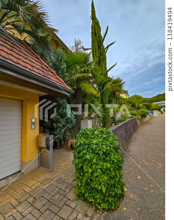 Charming street view in a European town with a traditional house covered in red ivy. Charming street view in a European town with a traditional house covered in red ivy. 138419494