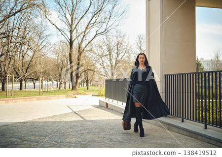 Woman walks on a sunny day in an urban area with trees and a building in view Woman walks on a sunny day in an urban area with trees and a building in view 138419512