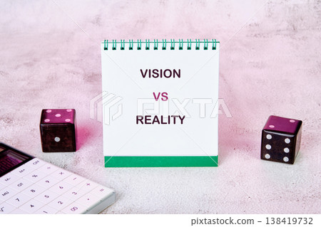 A conceptual scene presents a white notebook displaying VISION VS REALITY alongside two dice and a calculator, symbolizing planning and risk 138419732