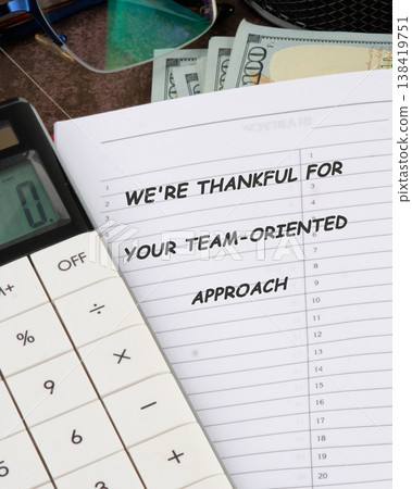 A heartfelt message of appreciation for teamwork sits on a desk, next to a calculator and multiple crisp US Dollar bills, signaling a rewarding moment A heartfelt message of appreciation for teamwork sits on a desk, next to a calculator and multiple crisp US Dollar bills, signaling a rewarding moment 138419751