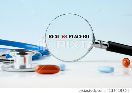 A keen eye observes REAL VS PLACEBO through a magnifying glass, positioned near a stethoscope and scattered bright pills, exploring drug trials 138419804