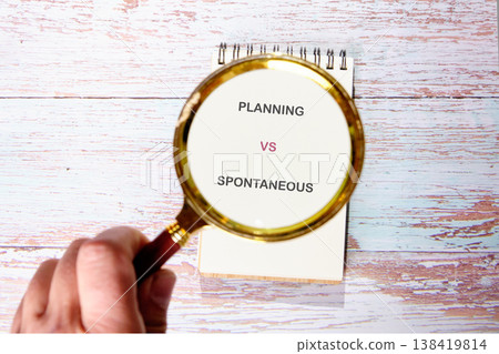 Considering planning vs. spontaneity, a key choice on a notebook atop weathered wood 138419814
