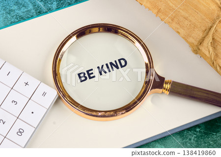 Be Kind emphasized by a golden magnifying lens, positioned on a crisp white notepad beside a white calculator Be Kind emphasized by a golden magnifying lens, positioned on a crisp white notepad beside a white calculator 138419860