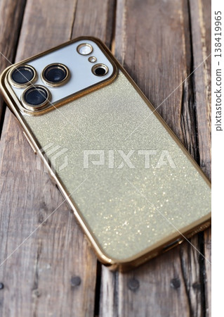 A triple-camera smartphone with a gold glitter back case. 138419965