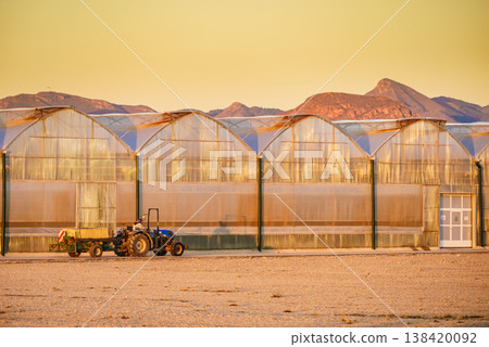 Tractor stands near large greenhouse. Region of Mazarron, Sierra de las Moreras in Murcia Spain. Tractor stands near large greenhouse. Region of Mazarron, Sierra de las Moreras in Murcia Spain. 138420092
