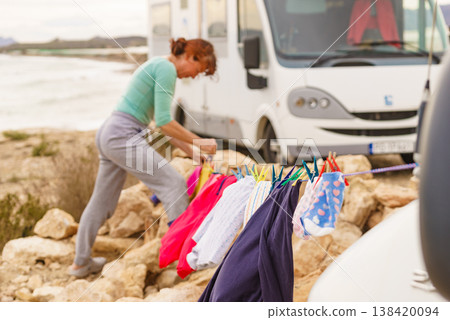 Woman hanging laundry on a clothesline by the beach with an RV in the background Woman hanging laundry on a clothesline by the beach with an RV in the background 138420094