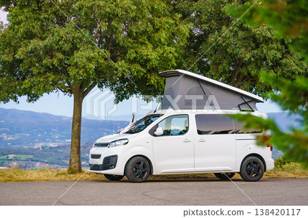 Camping setup with rooftop tent on van vehicle in green area during daytime in a natural setting Camping setup with rooftop tent on van vehicle in green area during daytime in a natural setting 138420117
