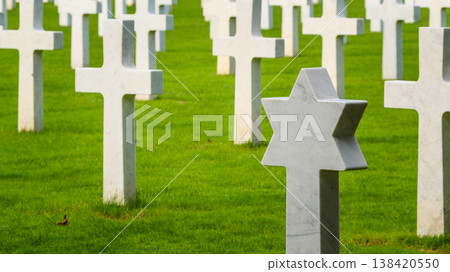 Gravestones stand in a cemetery with a star of David among crosses in the grassy field Gravestones stand in a cemetery with a star of David among crosses in the grassy field 138420550
