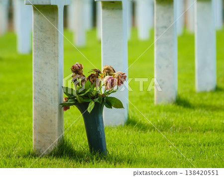Crosses stand in a row as flowers sit at a grave in a cemetery where people remember their loved ones 138420551