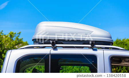 Silver roof box on a vehicle parked under blue sky. Travel, family vacation. Accessories for transportation. Silver roof box on a vehicle parked under blue sky. Travel, family vacation. Accessories for transportation. 138420558