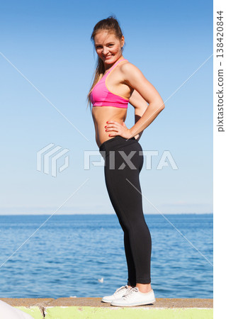 Woman in sportswear standing on dyke by sea Woman in sportswear standing on dyke by sea 138420844