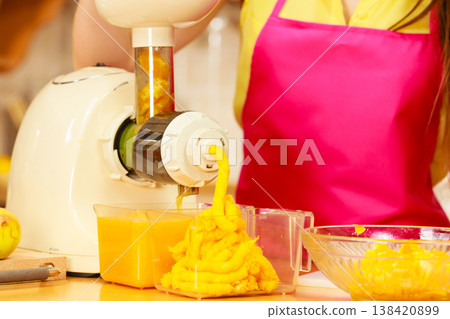 Woman making orange juice in juicer machine 138420899