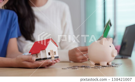 Family discussing savings with piggy bank and house model Family discussing savings with piggy bank and house model 138421007