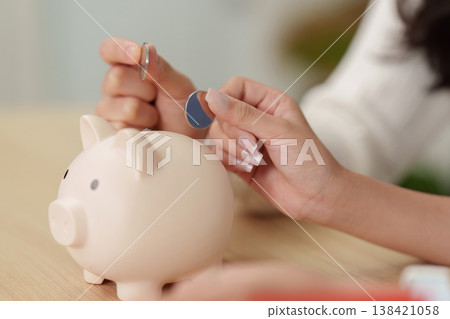 Hands saving coins in piggy bank for financial planning Hands saving coins in piggy bank for financial planning 138421058